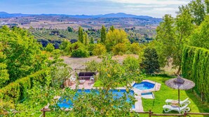 Un jardin avec une piscine, un espace barbecue et une vue sur la campagne.