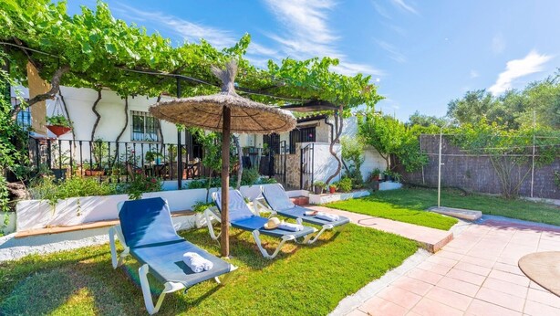 Een terras met loungestoelen en een pergola.