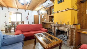 A cozy living room with a red sofa, a wooden coffee table, and a fireplace. - Bodega Ciprés Benaoján by Ruralidays (Málaga)