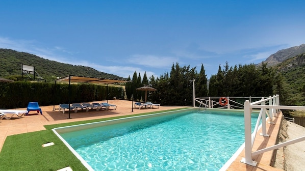 A rectangular swimming pool with clear blue water, surrounded by a white deck and a wooden walkway.