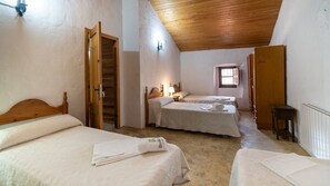 A room with two beds, wooden headboards, a wooden ceiling, and a small window. - Cortijo La Bodega - Conjunto Benaoján by Ruralidays (Málaga)