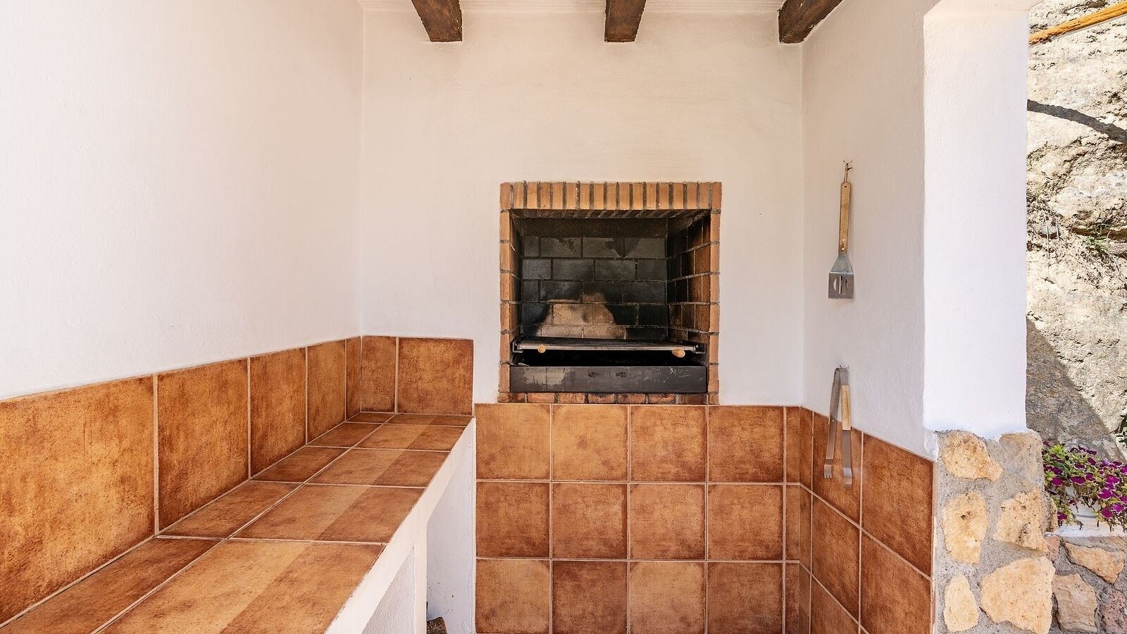 A tiled outdoor area with a brick fireplace, stone wall, and a wooden ladder.