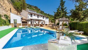 A swimming pool with a white tiled deck, a gazebo, and a building with a stone facade. - Iratxe Montefrío by Ruralidays (Granada)