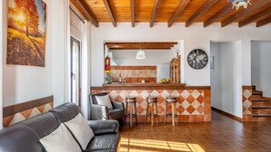 A cozy living room with a leather sofa, a kitchen area with a bar, and a staircase. - Iratxe Montefrío by Ruralidays (Granada)