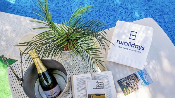 A table with a bottle of champagne, a book titled 'Rebelión en la granja', a brochure, and a towel with 'ruraldays' branding.