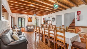A spacious dining area with wooden tables and chairs, a leather sofa, and a kitchen in the background. - Iratxe Montefrío by Ruralidays (Granada)
