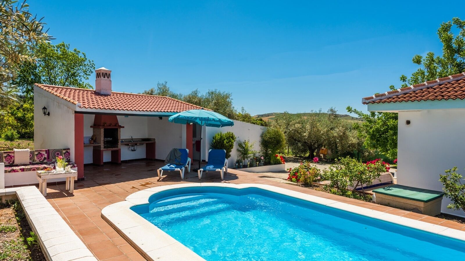 Una piscina con sillas de descanso y un porche cubierto.