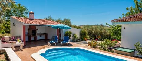 Una piscina con sillas de descanso y un porche cubierto.