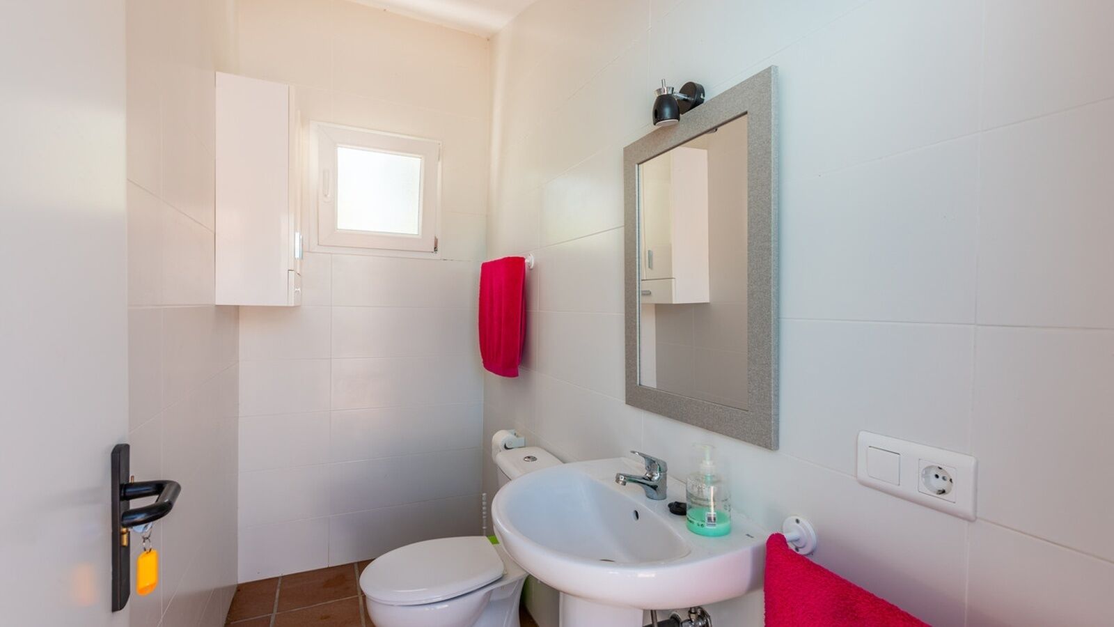 A small bathroom with a toilet, sink, and a mirror.