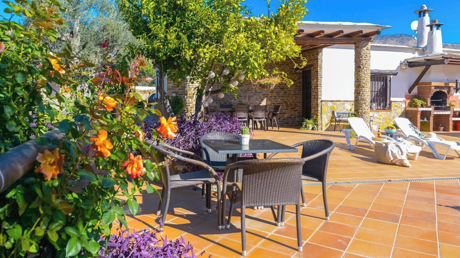 Une terrasse extérieure aménagée avec des meubles en osier, une table et un four en briques.