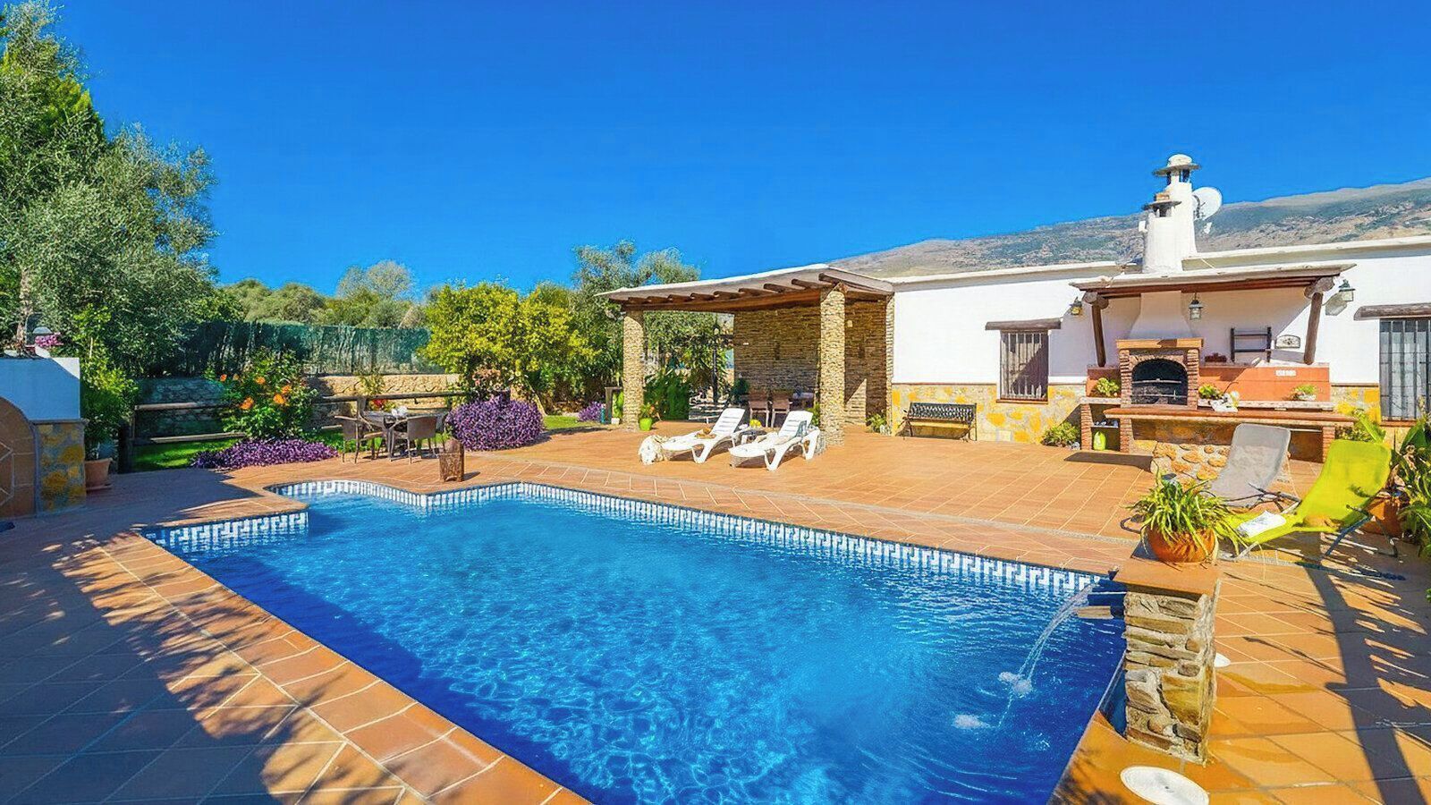 Une piscine avec des chaises longues et un espace barbecue.