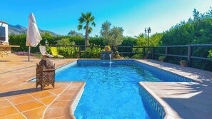 A swimming pool with a tiled edge, surrounded by a wooden fence, and a chair with an umbrella. - Al Hayón Órgiva by Ruralidays (Granada)
