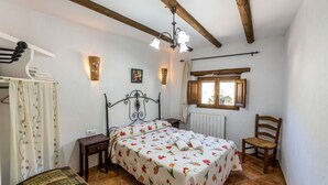 Quarto com cama, uma cadeira, janela e radiador.