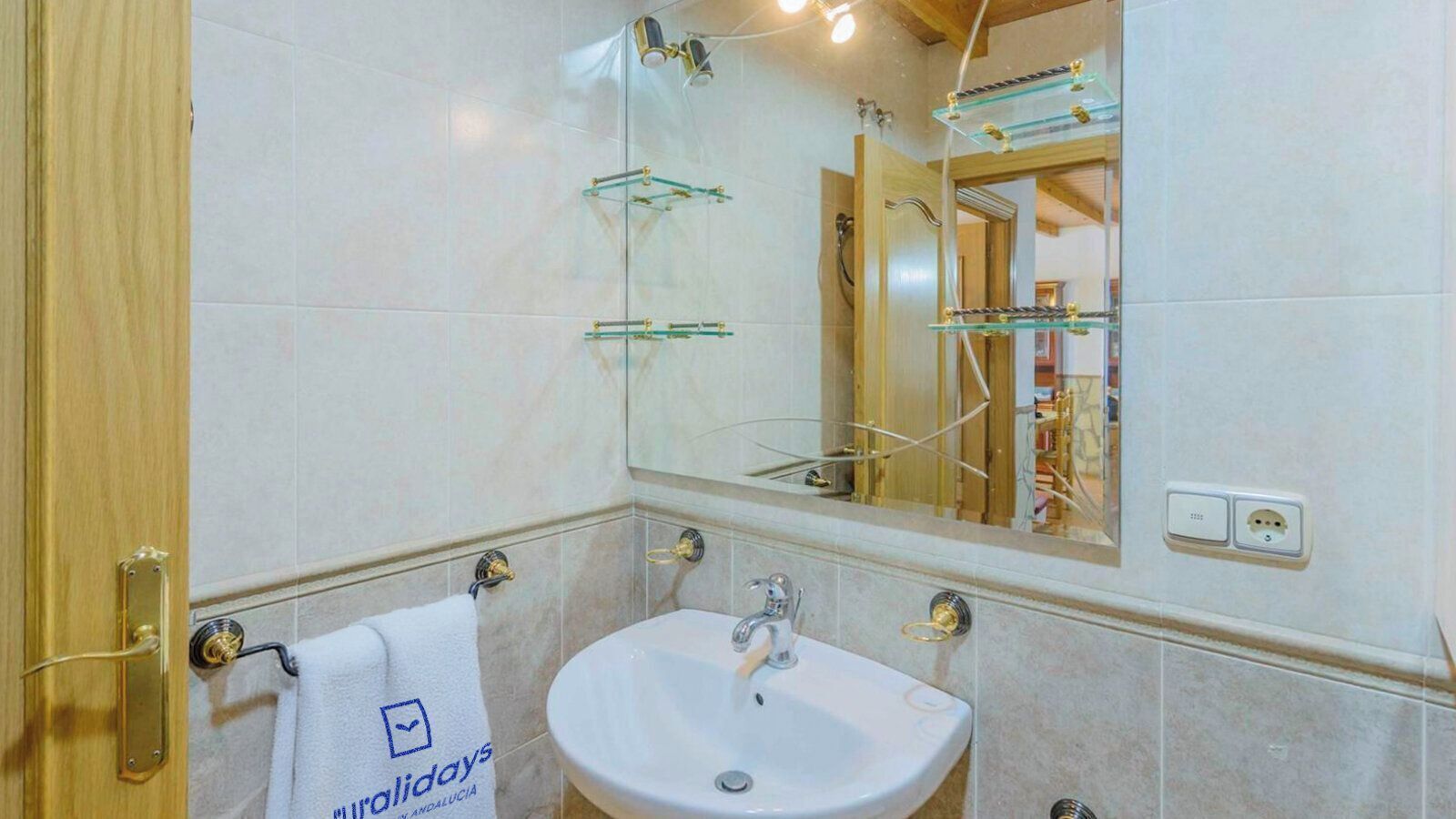 A bathroom with a white sink, a glass shower enclosure, and a towel with a logo.