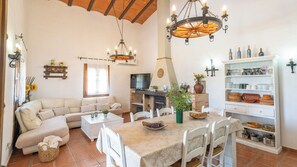 Uma sala de estar aconchegante com sofá, mesa de jantar e lareira.