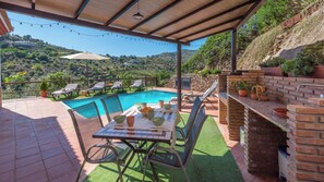 Un espace extérieur abrité comprenant une piscine, une table à manger, des chaises et un barbecue.