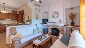 A living room with a fireplace, two sofas, a coffee table, and a TV. - Casa Amelia Cómpeta by Ruralidays (Málaga)