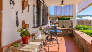 A patio with a stone table and chairs, a potted plant, and a view of the countryside.