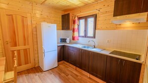 Een kleine keuken met houten kastjes, een koelkast, een magnetron en een spoelbak.