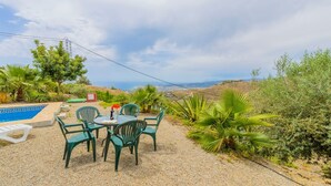 Een terras met een tafel en stoelen, een zwembadje en uitzicht op het landschap.