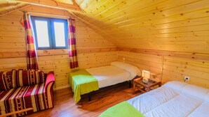Een gezellig chalet met twee bedden, een bank en een raam met gordijnen.