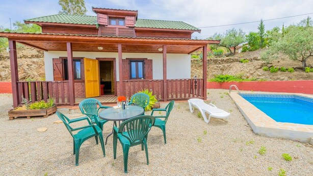 Een huis met een overdekte patio, een zwembad en buitenmeubels.