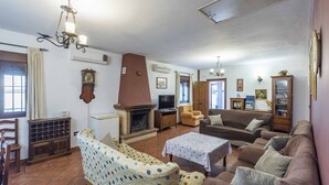 A living room with a fireplace, sofas, a television, and a patterned armchair.