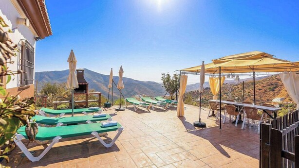 A terrace with sun loungers, a barbecue, and a table with chairs.