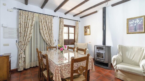 A dining area with a table, chairs, and a wood-burning stove.
