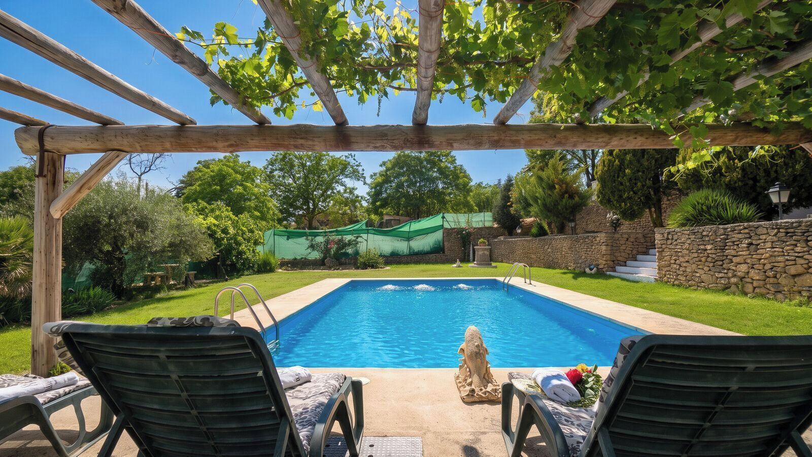 A swimming pool with two lounge chairs and a pergola overhead.