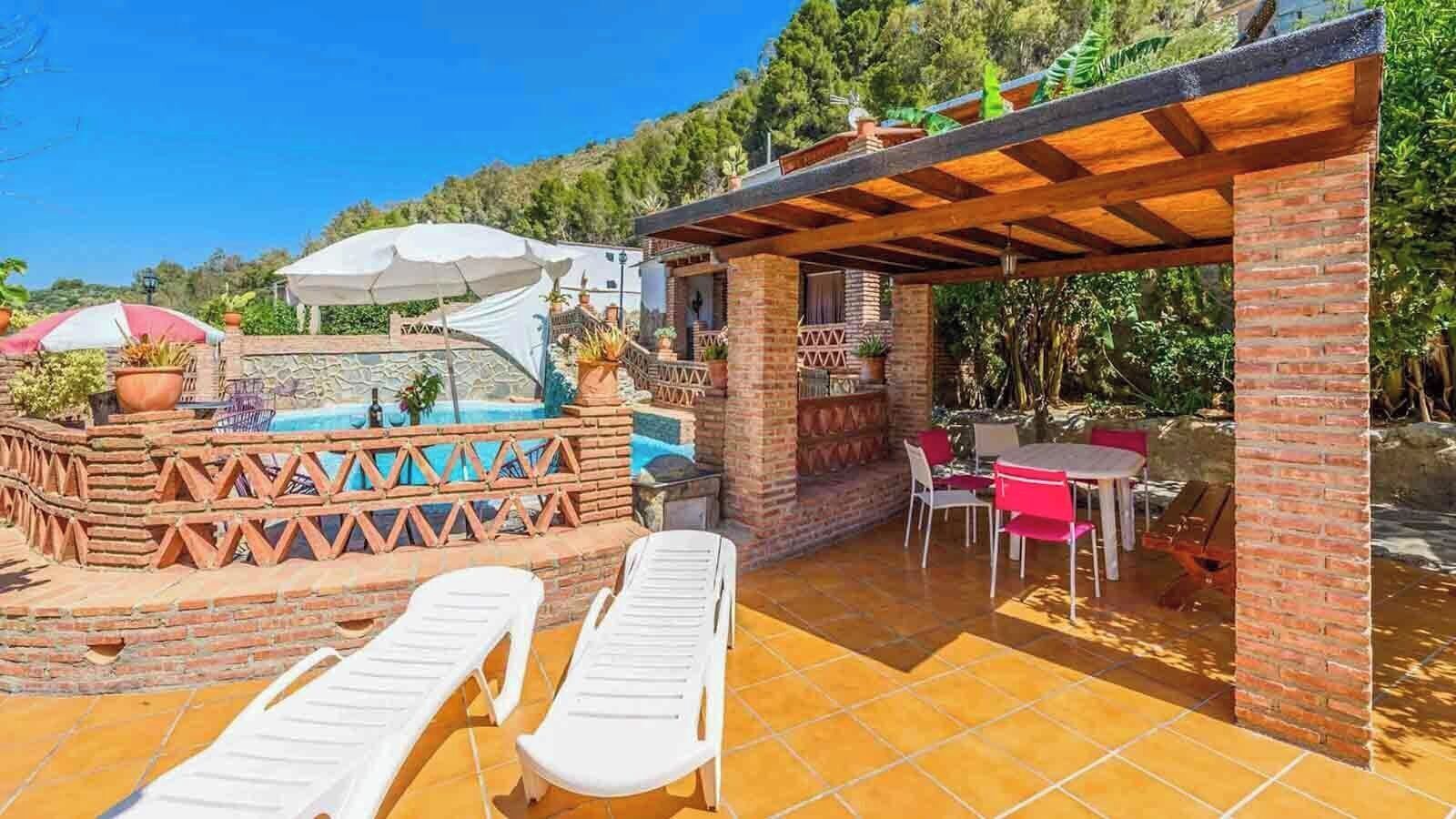 A patio area with a pool, lounge chairs, and a barbecue area.