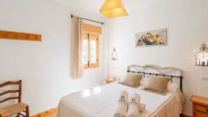 A bedroom with a bed, a chair, a nightstand, a lamp, and a painting on the wall. - Cuesta Blanca Montilla by Ruralidays (Córdoba)