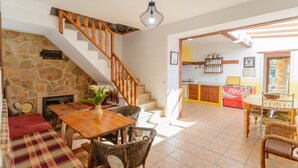 A spacious living area with a wooden staircase, a fireplace, and a dining area with wicker furniture. - Cuesta Blanca Montilla by Ruralidays (Córdoba)
