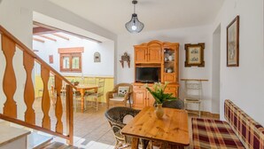 A cozy living room with a wooden dining table, wicker chairs, a sofa, and a television. - Cuesta Blanca Montilla by Ruralidays (Córdoba)