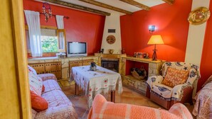 A cozy living room with a fireplace, a television, and a dining area with a table and chairs. - Cortijo San Jose Iznájar by Ruralidays (Córdoba)
