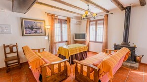 Una habitación acogedora con una cama de madera, una mesita pequeña, un televisor y un estufa de leña.