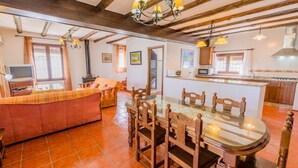 Una sala de estar acogedora con un sofá, una mesa de comedor con superficie de vidrio, sillas de madera y una zona de cocina con microondas y armarios.