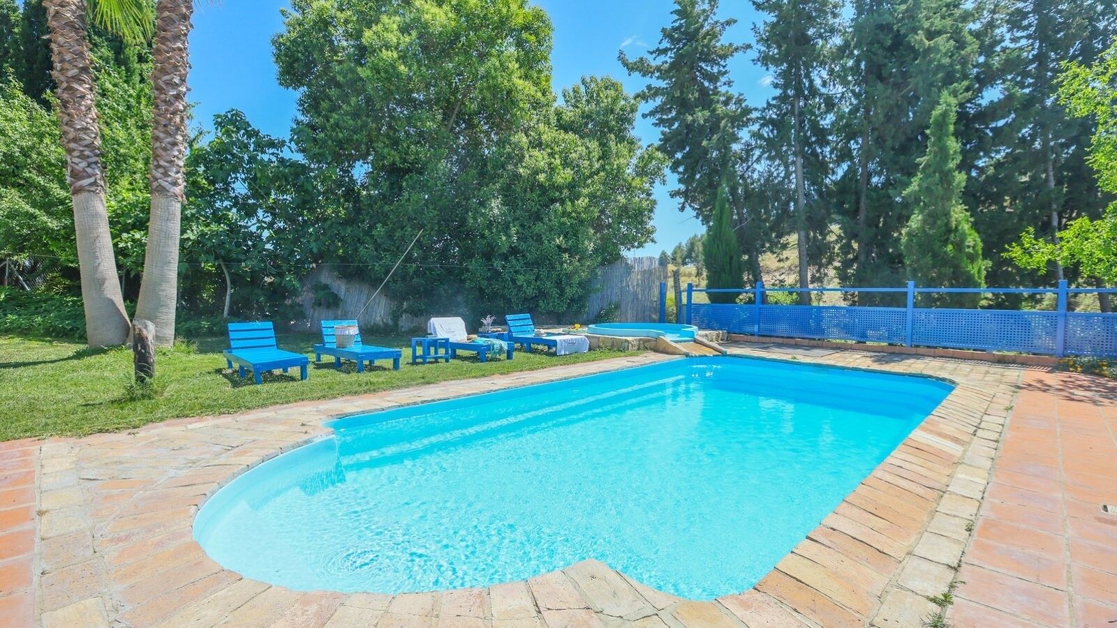 A rectangular swimming pool with a tiled edge, surrounded by a brick patio.