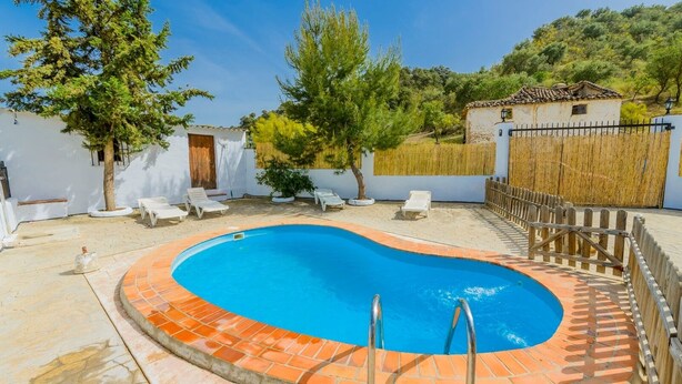 Una piscina con borde de azulejos, rodeada de paredes blancas y una valla de madera.