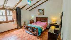 Un dormitorio con una cama de madera, una mesita de noche, un radiador y una ventana con cortinas.