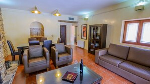 A living room with a sofa, armchairs, a dining table, and a fireplace. - Los Albardinales - Casa Picual Tabernas by Ruralidays (Almería)