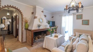 Una sala de estar acogedora con chimenea, un conjunto de sofá, una televisión y una mesa de comedor.