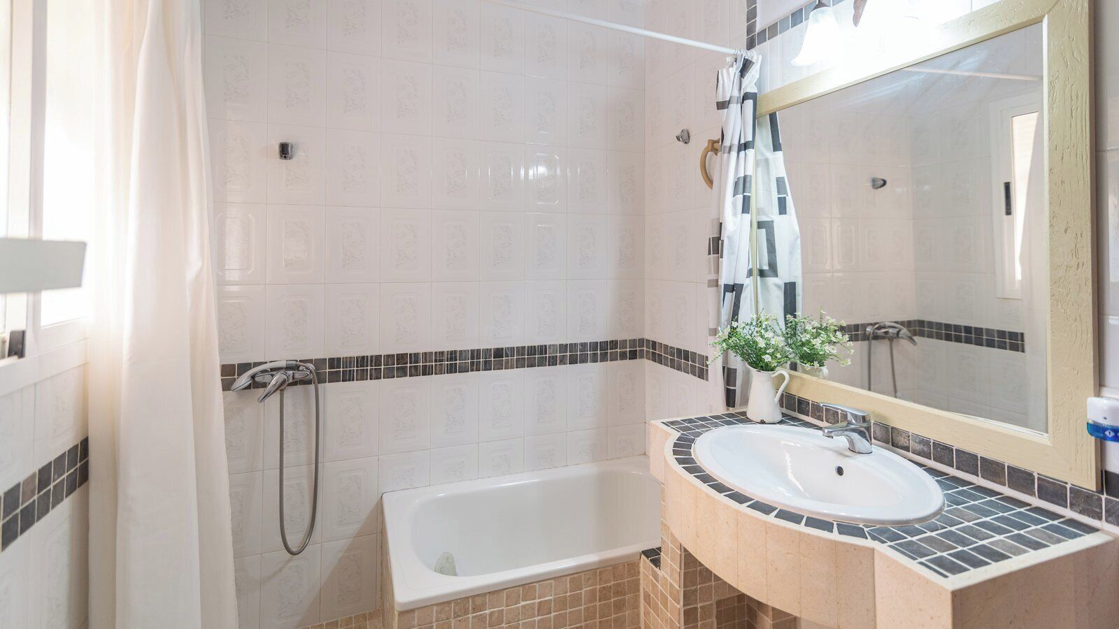 Un baño con bañera, lavamanos con espejo y cabina de ducha.