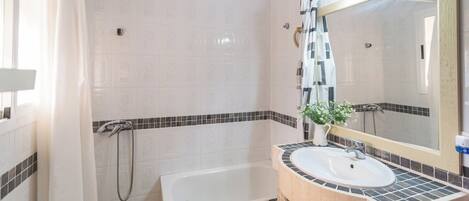 Un baño con bañera, lavamanos con espejo y cabina de ducha.