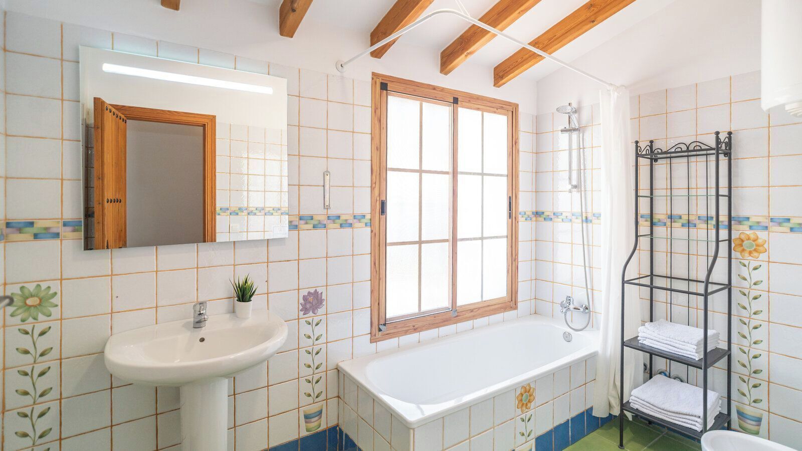 A bathroom with a sink, window, bathtub, and towel rack.