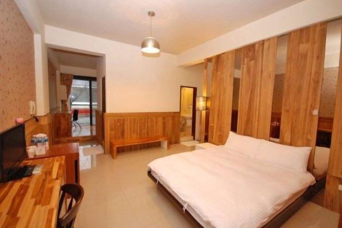 Un dormitorio con cabecera de madera, una cama individual, un escritorio con silla y una lámpara colgante.
