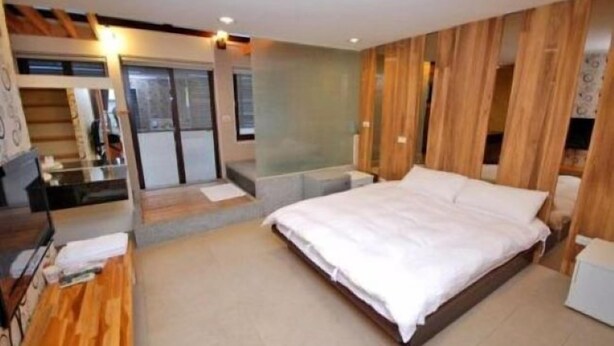 Una camera da letto moderna con un letto grande, pannelli in legno alle pareti e una piccola scrivania con una sedia.