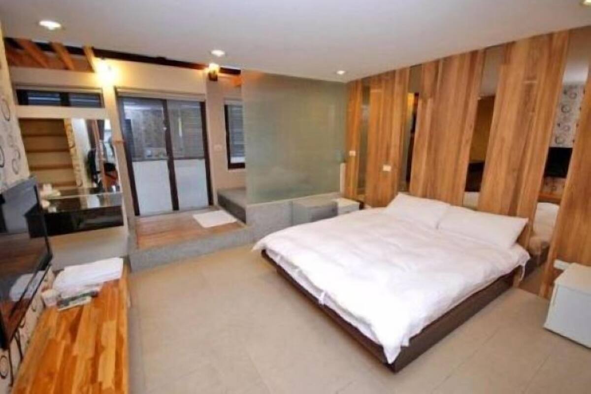 Un dormitorio moderno con una cama grande, paneles de madera en las paredes y un escritorio pequeño con una silla.