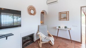 A living room with a fireplace, a television, a comfortable chair, and a small table with candles.