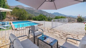 A poolside area with a view of mountains, a pool, and outdoor seating.